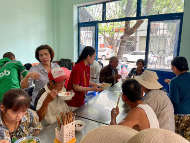 a CodeComplete volunteer respectfully serves another local Da Nang community members